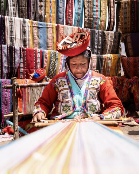 older woman in bright clothing hand weaving