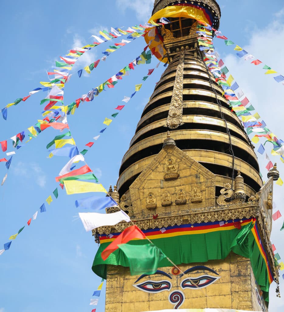 bright stupa with prayer flags and blue sky