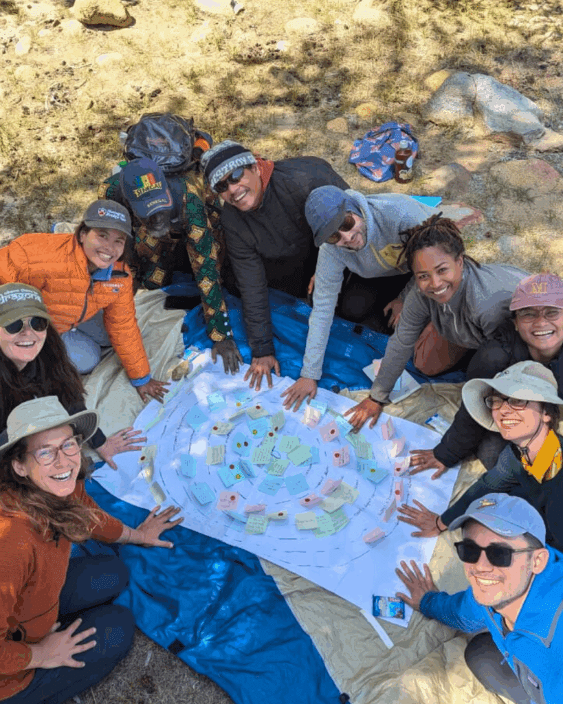 group sitting on ground looking up smiling with stick notes on paper