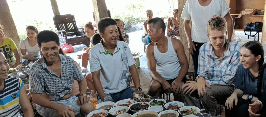 people sitting around a table full of food laughing