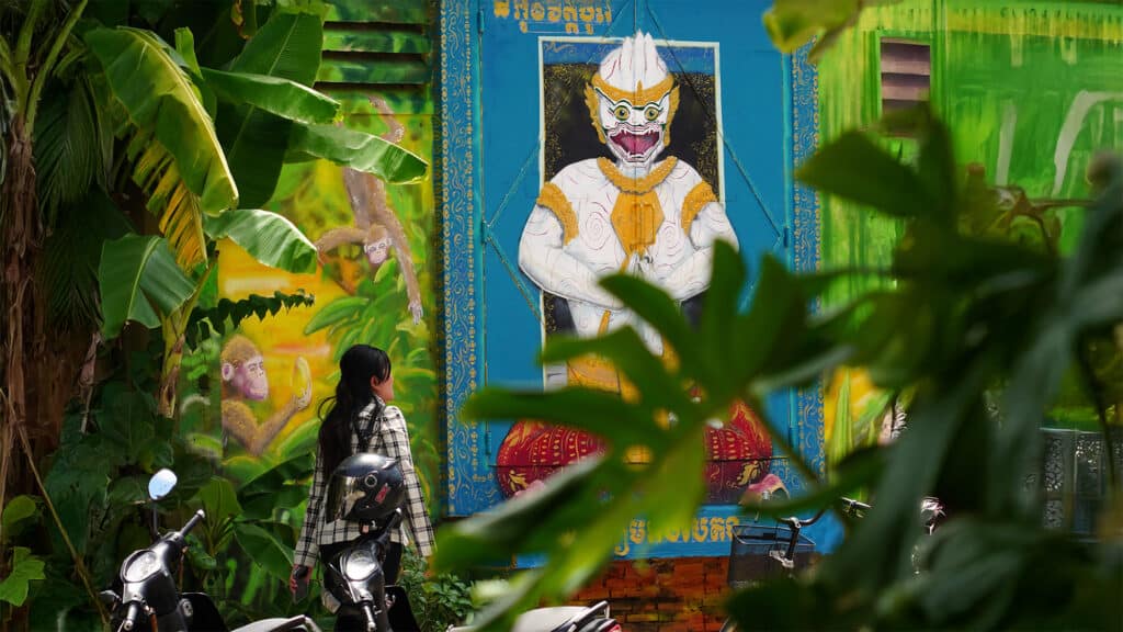 mural surrounded by green plants and woman looking at it