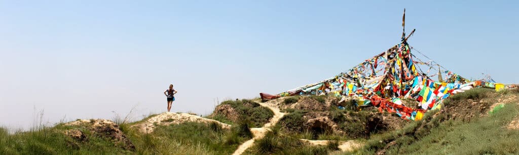 girl standing on trail looking at prayer flags