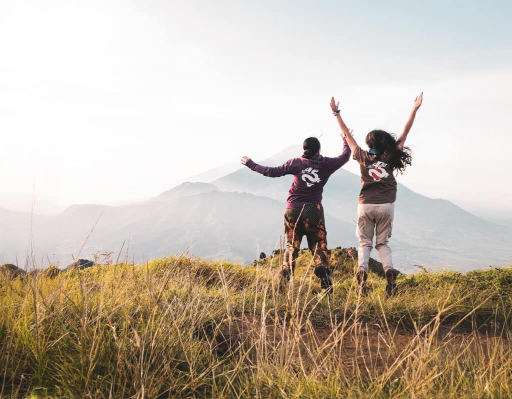 two people jumping in front of mountain