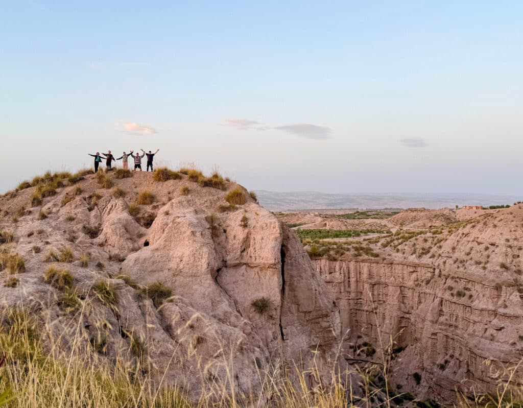 five silhouettes on top of cliff at sunset