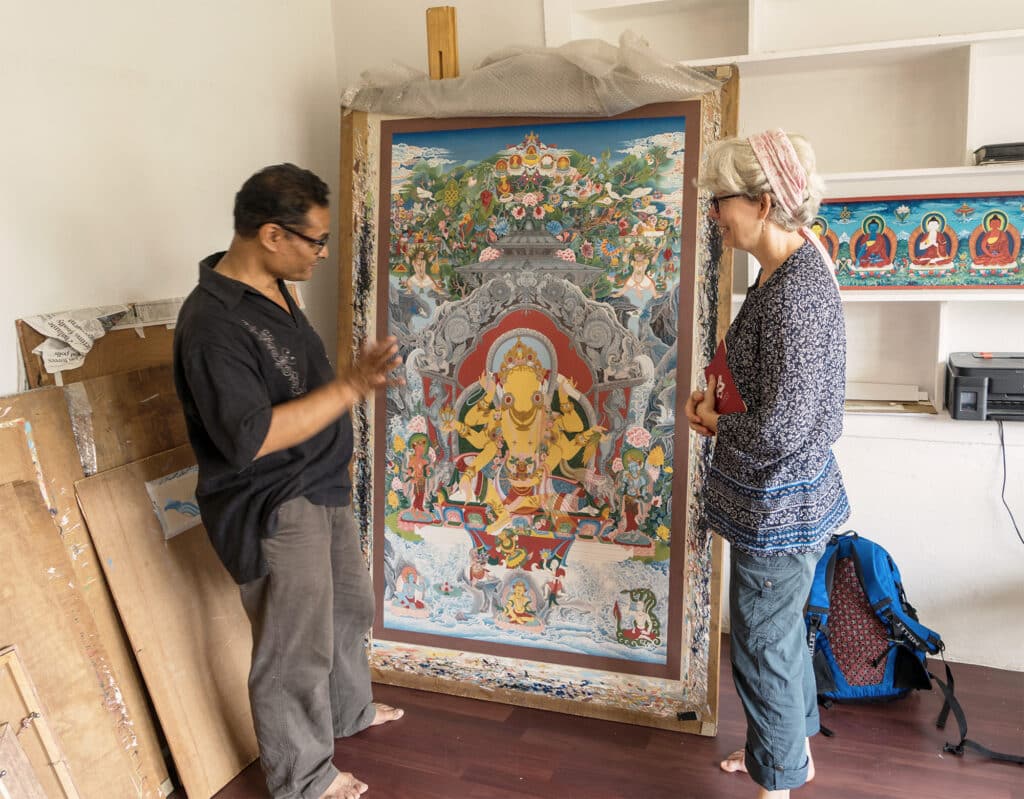 people standing in front of large thanka painting