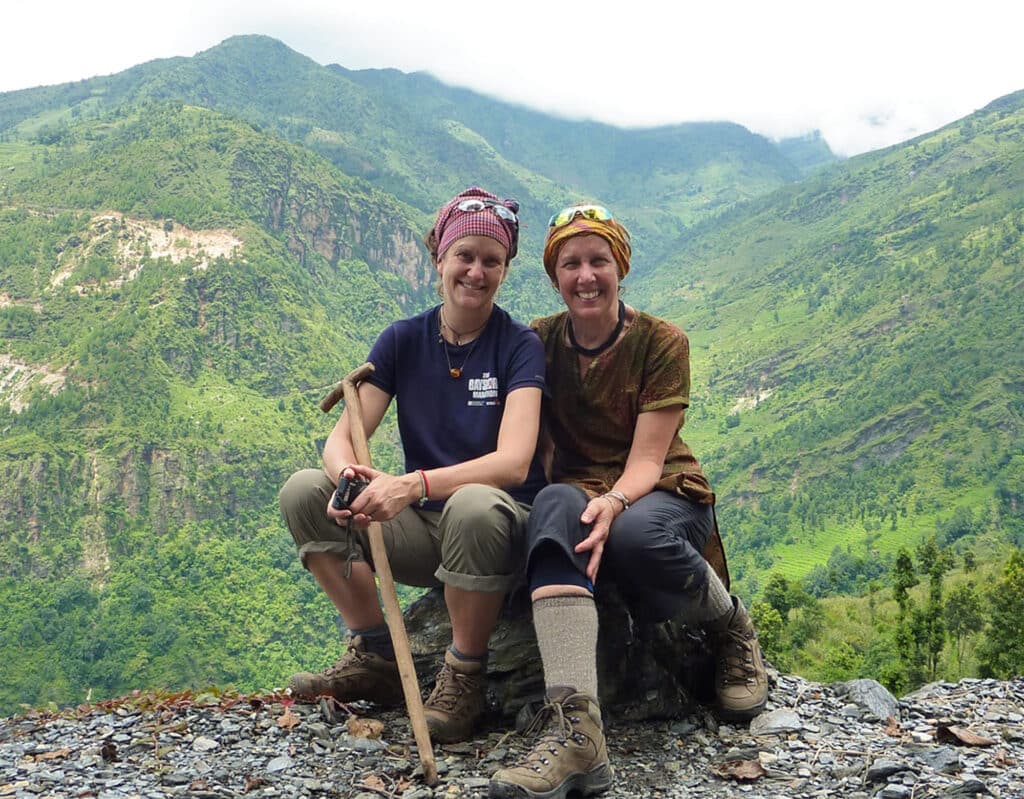 two women sitting on rock by trail