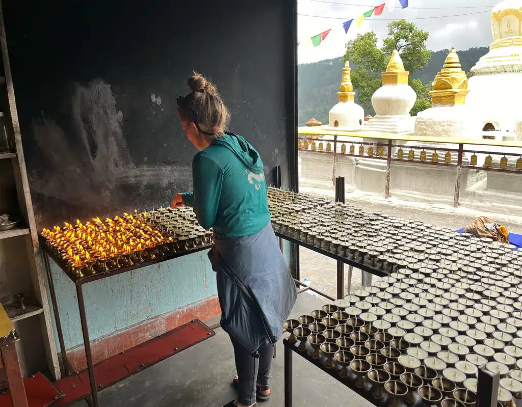 person lighting candles with stupas in background