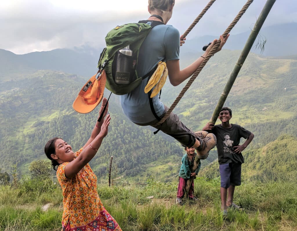 woman pushing girl on large outdoor swing