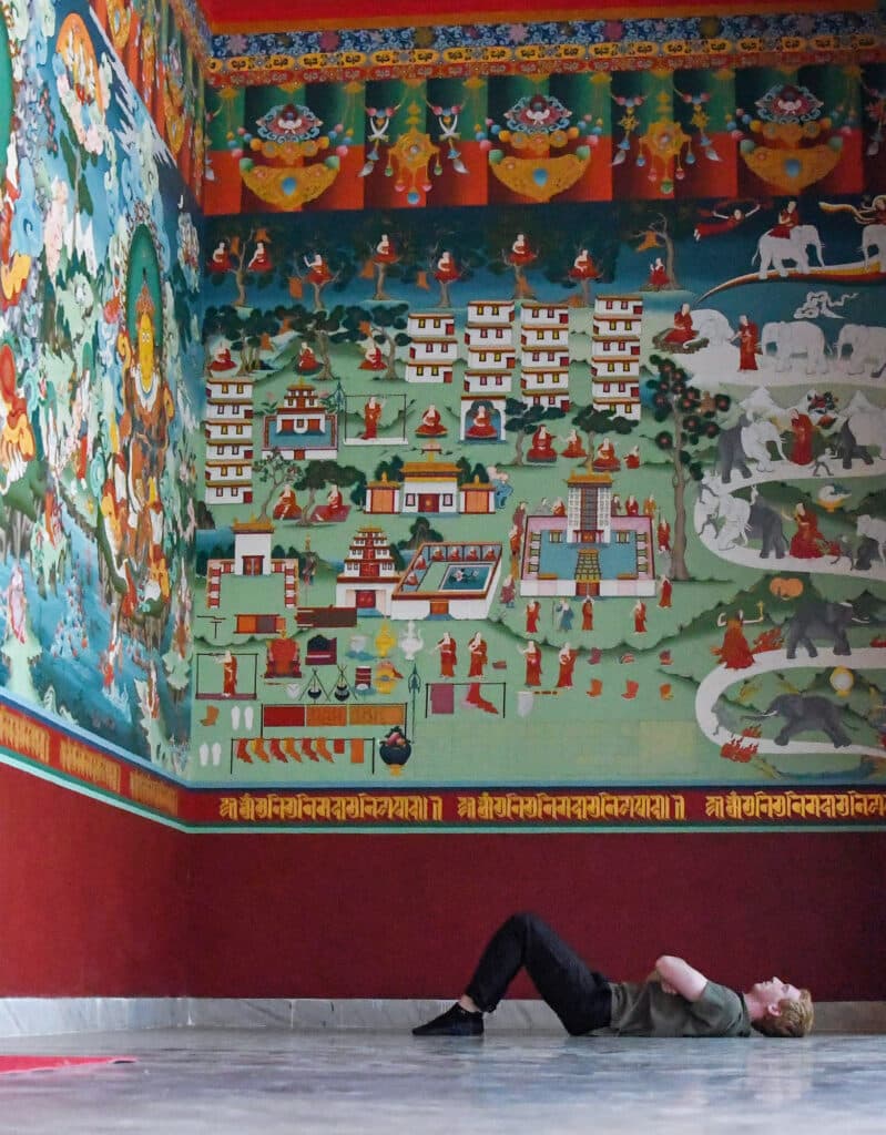 person laying on floor looking at large paintings on wall