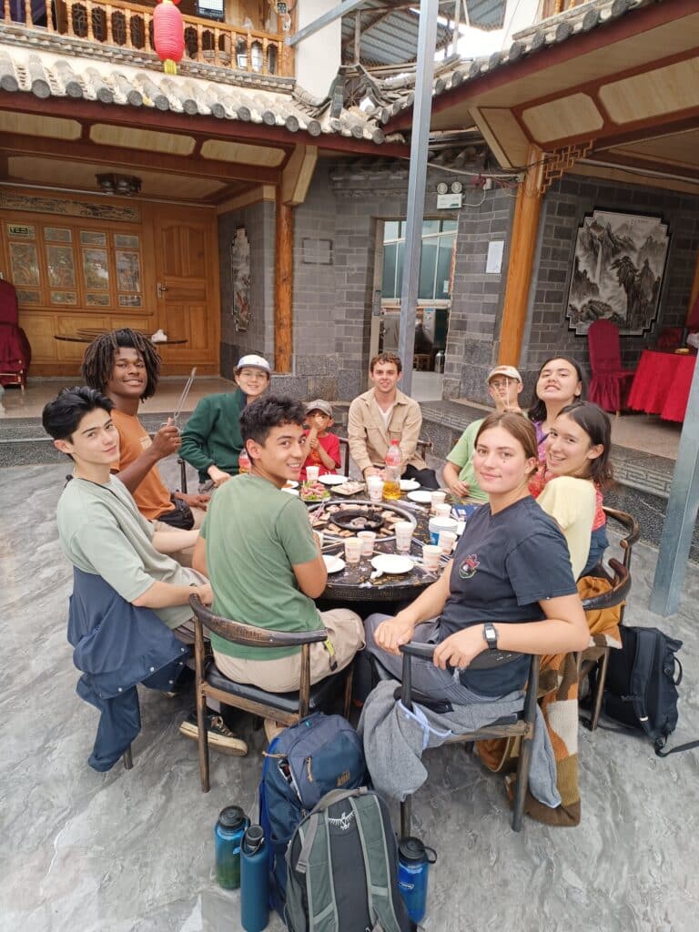 group seated at outdoor table eating grilled food