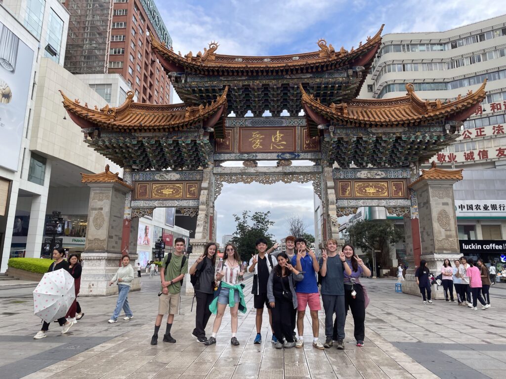 group smiling in front of ornate Chinese arch to city