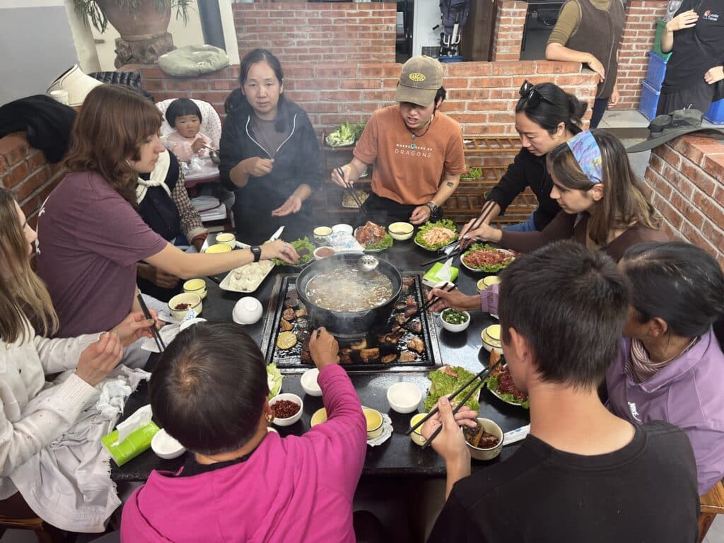 people sitting around table with grill in center