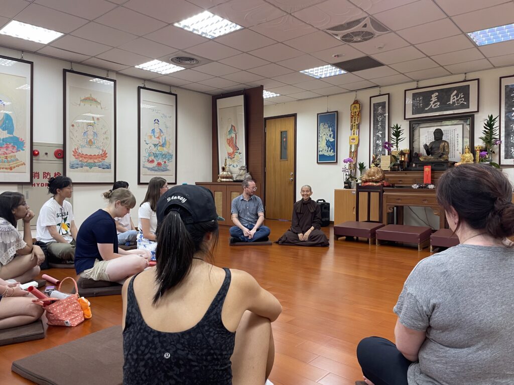 group sitting in circle in room with paintings on wall