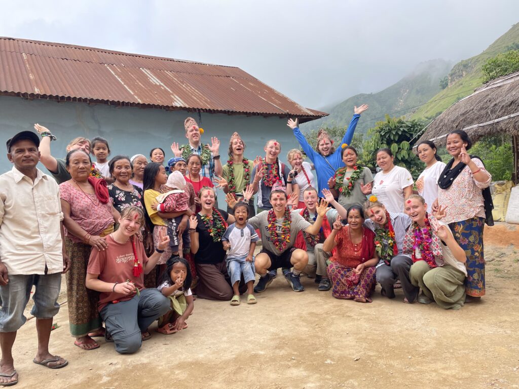group with flower garlands smiling and waving at camera
