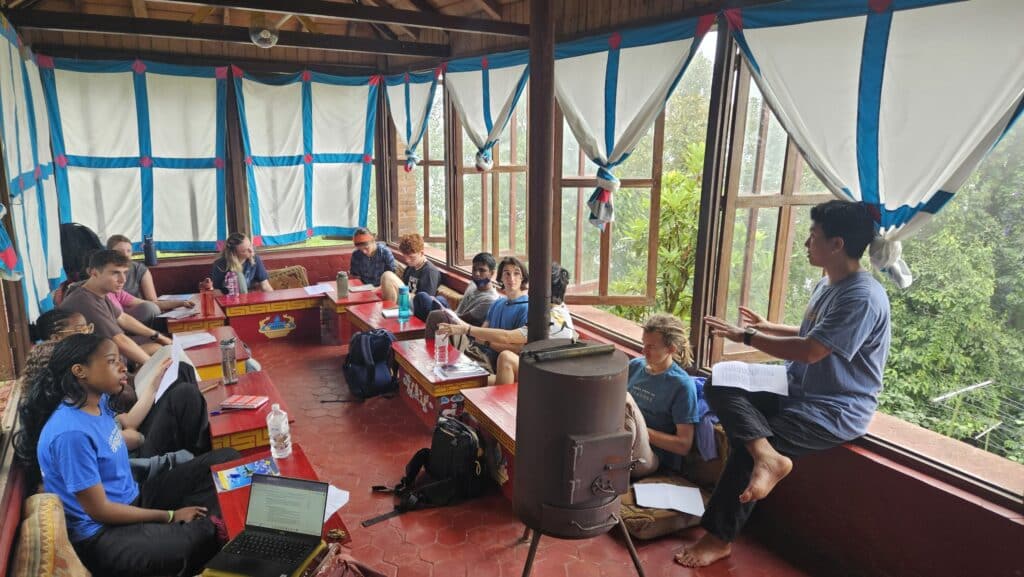 Group seated at small red desks listening to person talk