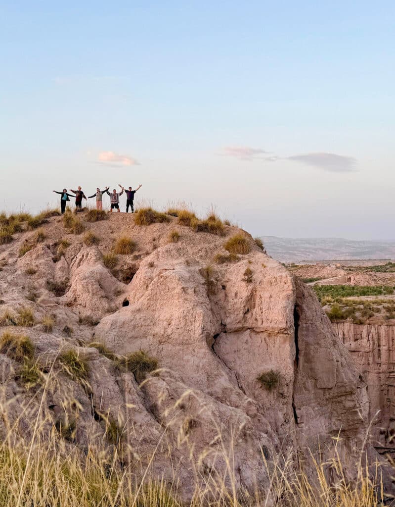 five silhouettes on top of cliff at sunset